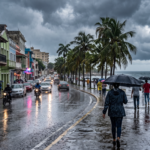 Calle de una ciudad del Caribe bajo la lluvia con personas usando paraguas
