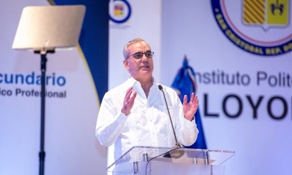 El presidente Luis Abinader, con camisa blanca y lentes, habla desde un atril transparente ante un fondo con el nombre del Instituto Politécnico Loyola.