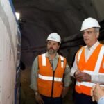 Abinader supervisa el túnel pluvial de la avenida Luperón en Santo Domingo Luis Abinader, con casco blanco y chaleco reflectante, observa planos de obra dentro de un túnel junto a otros dos hombres con equipo de seguridad.