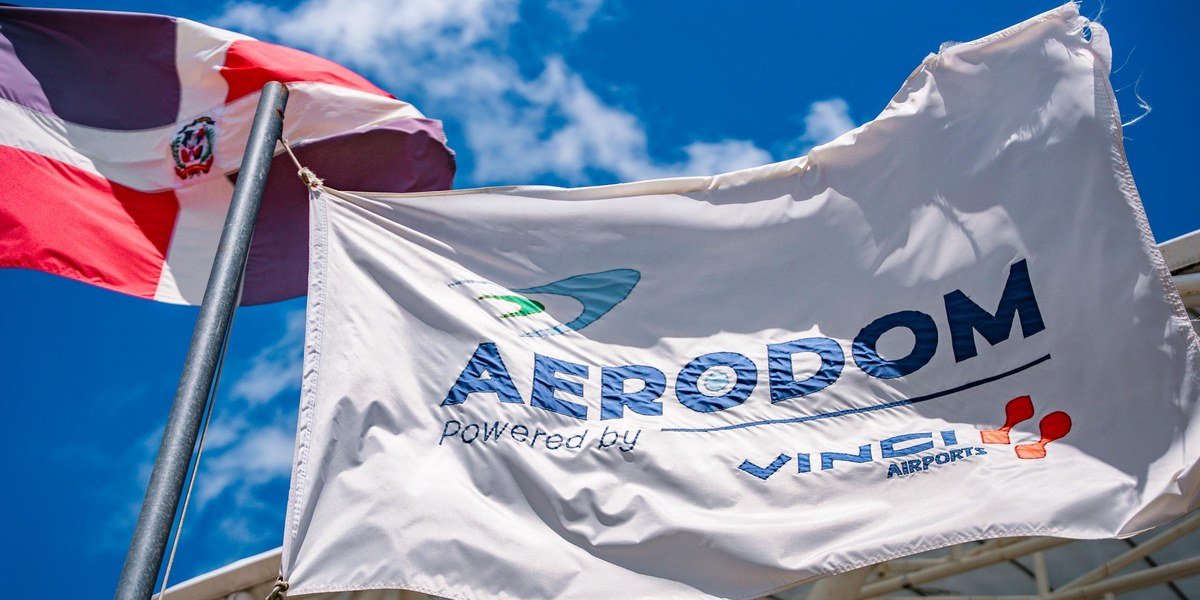 Bandera de AERODOM junto a la bandera dominicana en un aeropuerto