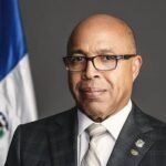Reforma al Código de Trabajo permanece paralizada por falta de consenso entre sectores Alfredo Pacheco, con gafas y traje a cuadros, posa junto a la bandera dominicana