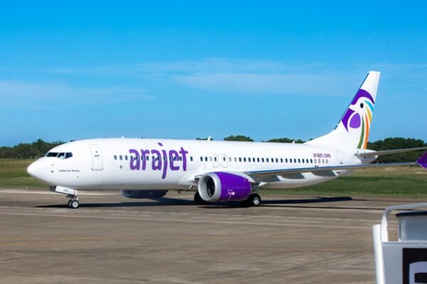 Avión Boeing 737 MAX de Arajet, blanco con el logotipo morado, en la pista de un aeropuerto con cielo despejado