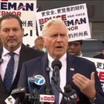 Bruce Blakeman habla ante micrófonos de varios medios, rodeado de simpatizantes con carteles de su candidatura a gobernador