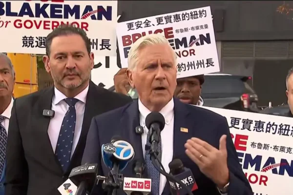 Bruce Blakeman habla ante micrófonos de varios medios, rodeado de simpatizantes con carteles de su candidatura a gobernador