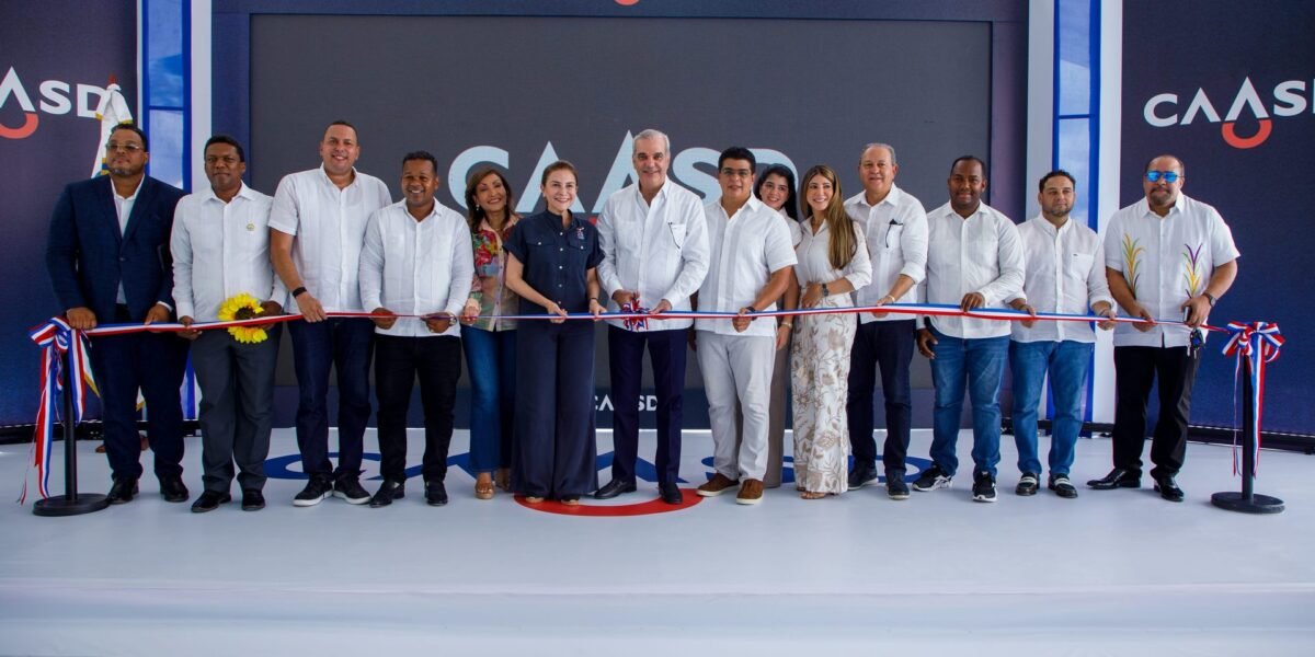 El presidente Luis Abinader corta una cinta tricolor en una tarima de la Caasd, junto a una fila de hombres y mujeres; uno de ellos sostiene un girasol.