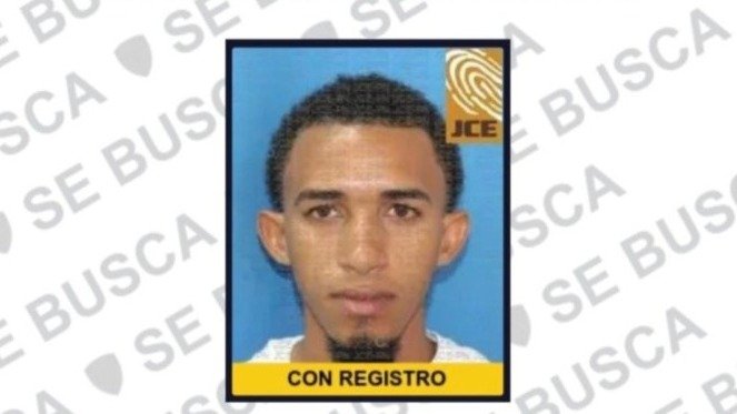 Foto de cédula de un hombre joven de cabello rizado y perilla, dentro de una ficha de búsqueda con la leyenda «SE BUSCA»