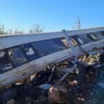 Un vagón de alta velocidad de Renfe, destrozado y volcado, con las ventanas rotas y restos metálicos esparcidos alrededor.