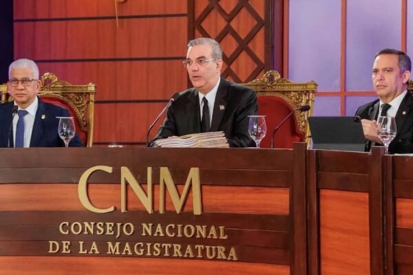 Luis Abinader habla al micrófono en el centro de la mesa del Consejo Nacional de la Magistratura, junto a otros dos miembros del consejo.