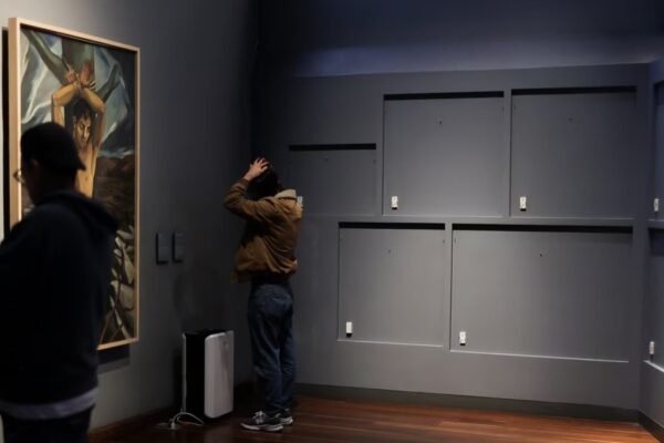 Visitantes en una sala del Museo Nacional de Colombia junto a un muro gris del que se retiraron las piezas expuestas