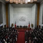 Vista general del hemiciclo del Congreso Nacional de Chile durante una sesión solemne, con el escudo nacional y banderas chilenas al fondo y las tribunas llenas