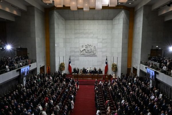 Vista general del hemiciclo del Congreso Nacional de Chile durante una sesión solemne, con el escudo nacional y banderas chilenas al fondo y las tribunas llenas