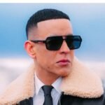 Rosalía y Daddy Yankee, entre los primeros artistas del Latin Grammy 2026 Daddy Yankee con gafas oscuras, camisa blanca, corbata negra y chaqueta de cuero con cuello de borrego, al aire libre.