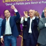 Danilo Medina aplaude junto a otros dirigentes del PLD frente a un telón morado del partido