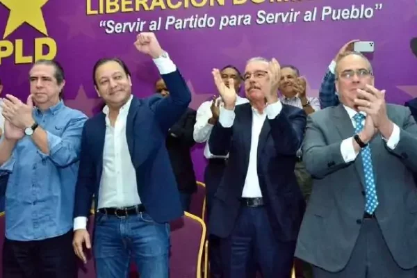 Danilo Medina aplaude junto a otros dirigentes del PLD frente a un telón morado del partido