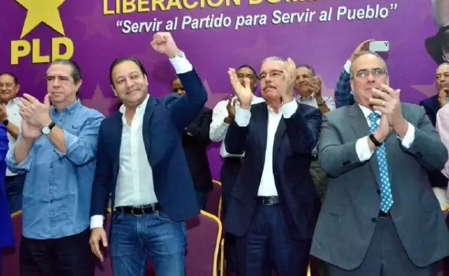 Danilo Medina aplaude junto a otros dirigentes del PLD frente a un telón morado del partido