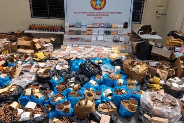 Puros en sacos y cajas, botellas de mamajuana y otras mercancías decomisadas expuestas en el patio del Ceccom, frente a un letrero de la institución
