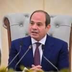 El presidente egipcio Abdelfatah al Sisi habla ante micrófonos, sentado en un sillón junto a la bandera de Egipto