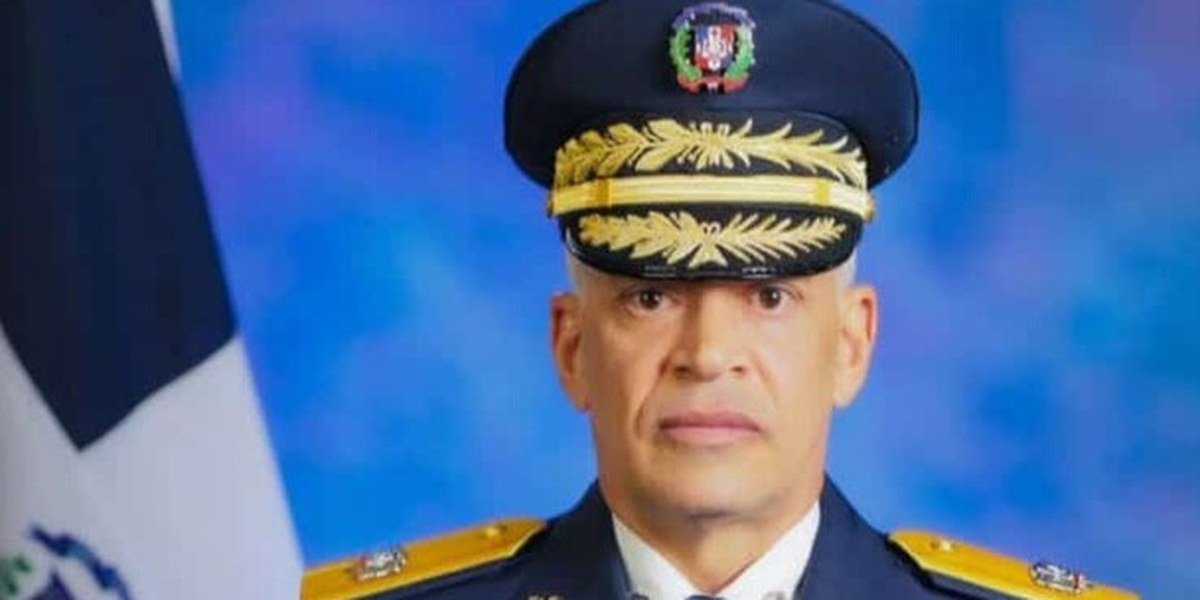 Retrato oficial de Ernesto Rafael Rodríguez García con uniforme de gala y gorra de oficial, junto a la bandera dominicana.