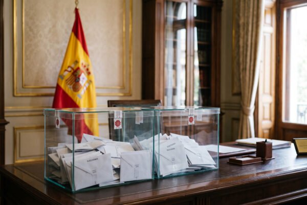 Urnas electorales y bandera de España en entorno gubernamental