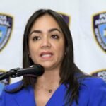 Interior y Policía abre gracia para renovar licencias de armas vencidas Faride Raful habla ante un micrófono, con chaqueta azul, frente a un fondo con escudos de la Policía Nacional.