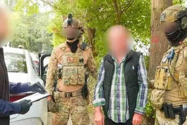 Agentes de fuerzas especiales junto a un detenido con el rostro difuminado, al lado de un automóvil blanco