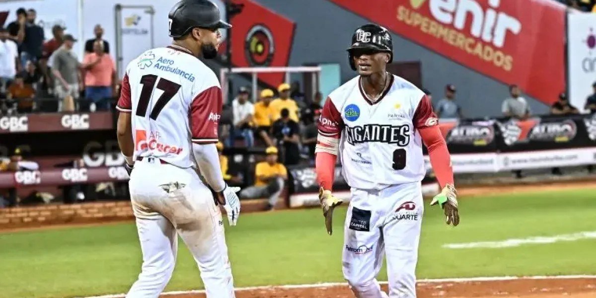 Dos jugadores de los Gigantes del Cibao se saludan en el home tras anotar carrera