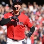 Un jugador de los Guardianes de Cleveland, con uniforme rojo, celebra mientras recorre las bases ante el público