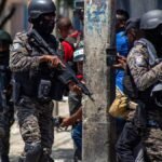 Haití intensifica la búsqueda de cuatro militares salvadoreños emboscados Agentes con uniforme de camuflaje, casco y fusiles avanzan por una calle mientras reporteros gráficos toman imágenes