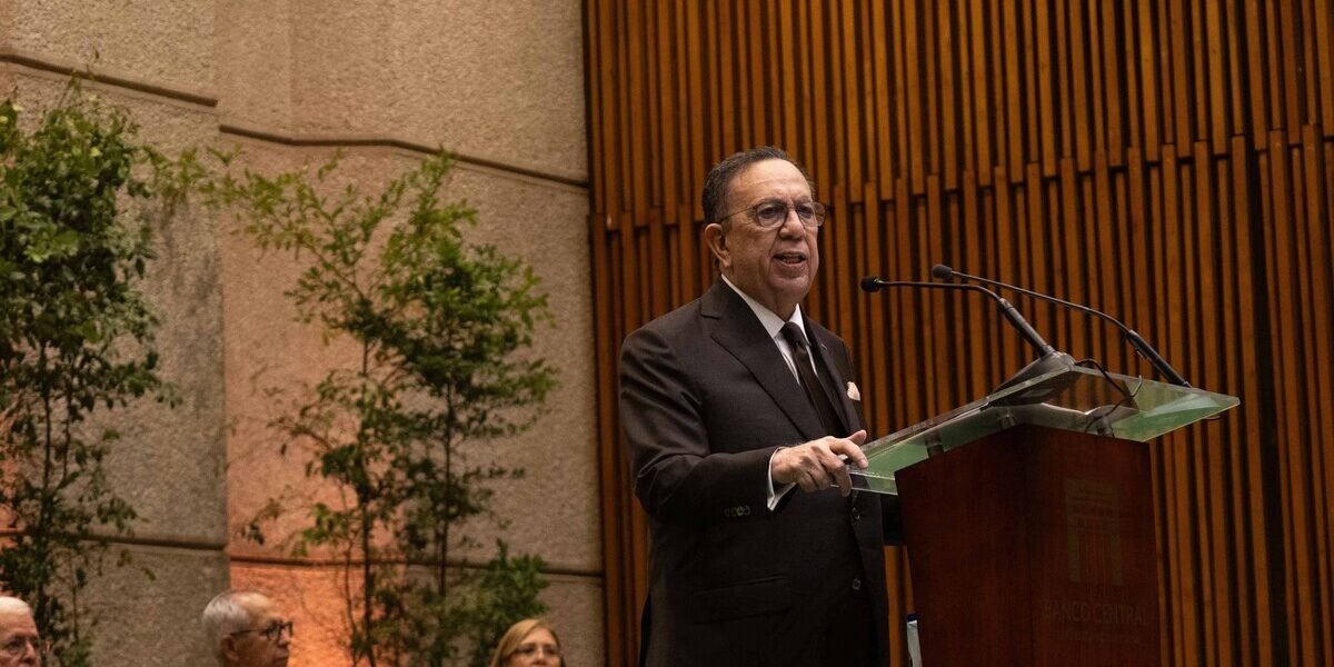 Héctor Valdez Albizu habla desde un atril del Banco Central ante un auditorio