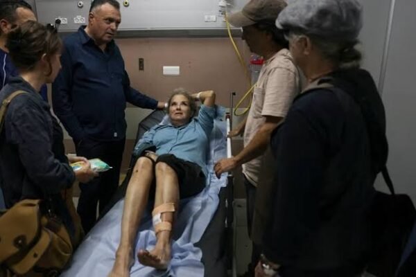 Una mujer con una pierna vendada, tendida en una camilla de hospital, rodeada de varias personas