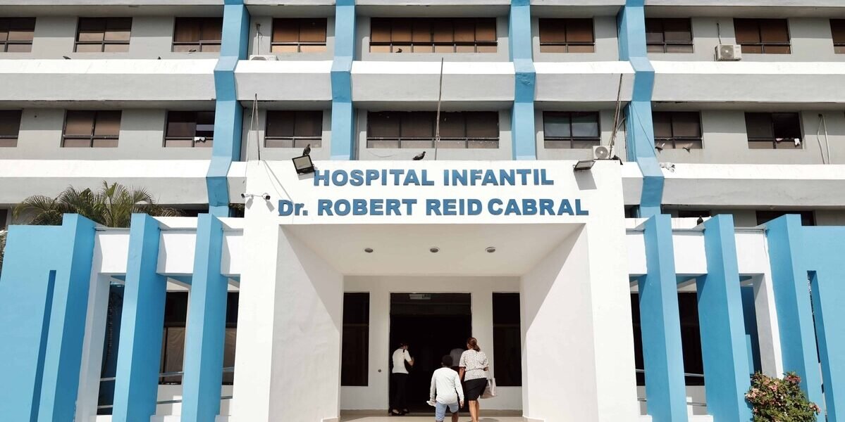 Fachada blanca y azul del Hospital Infantil Doctor Robert Reid Cabral, con su nombre sobre la entrada principal y varias personas entrando