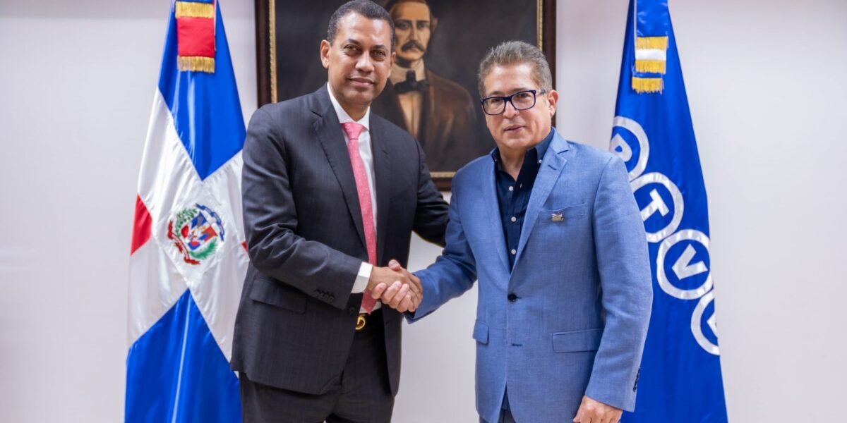 Dos hombres de traje se dan la mano entre la bandera dominicana y una bandera azul de la CERTV, frente a un retrato de Duarte.