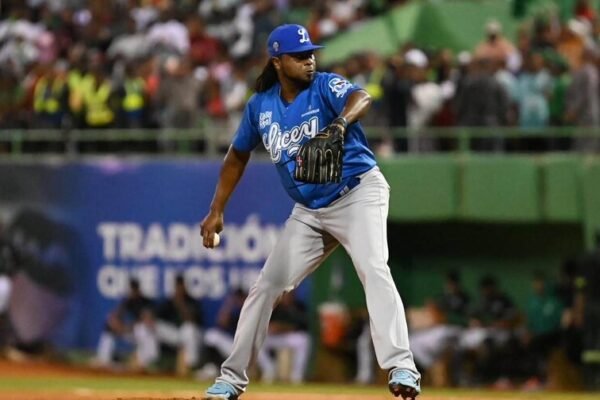 Lanzador con uniforme azul de los Tigres del Licey se prepara para lanzar desde el montículo, con el estadio lleno al fondo.