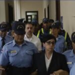 Agentes de la Policía Nacional escoltan a un hombre y a una mujer por un pasillo de un edificio judicial