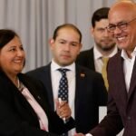 Jorge Rodríguez, presidente del Parlamento venezolano, sonríe mientras estrecha la mano de una mujer durante un acto oficial.