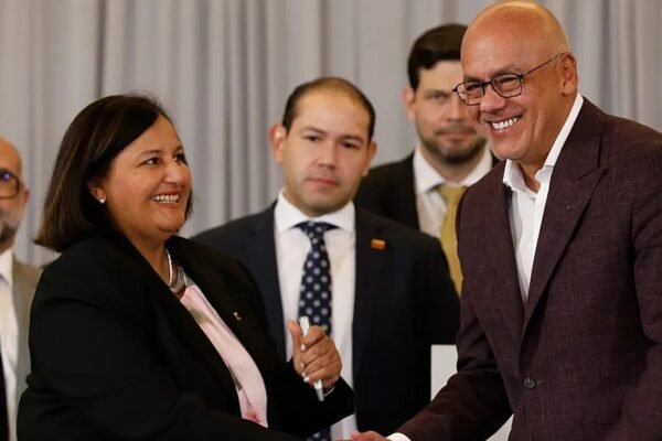 Jorge Rodríguez, presidente del Parlamento venezolano, sonríe mientras estrecha la mano de una mujer durante un acto oficial.