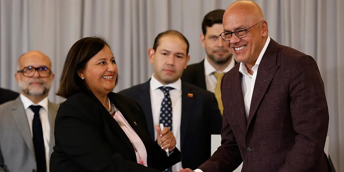Jorge Rodríguez, presidente del Parlamento venezolano, sonríe mientras estrecha la mano de una mujer durante un acto oficial.