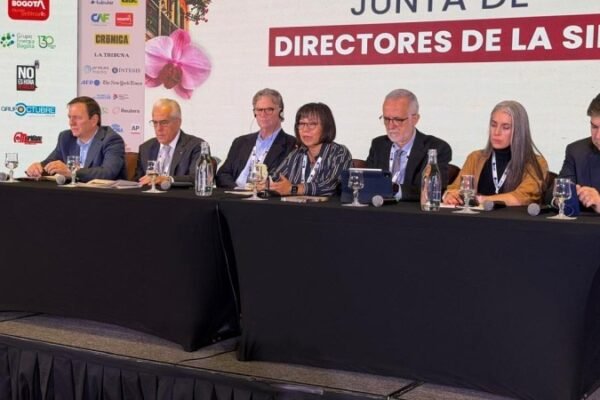 Siete personas sentadas en una mesa con micrófonos ante un panel que dice Junta de Directores de la SIP