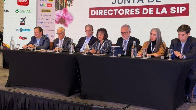 Siete personas sentadas en una mesa con micrófonos ante un panel que dice Junta de Directores de la SIP