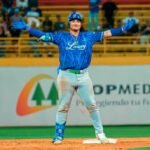 Un jugador de los Tigres del Licey con casco y uniforme azul abre los brazos para celebrar sobre la segunda base