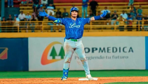 Un jugador de los Tigres del Licey con casco y uniforme azul abre los brazos para celebrar sobre la segunda base