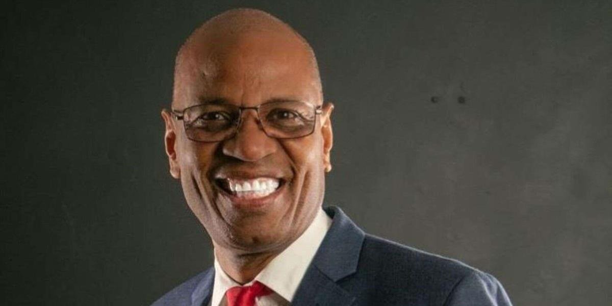Luis Pérez, presidente del Colegio Dominicano de Periodistas, sonríe con gafas, saco azul y corbata roja