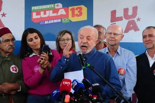 Luiz Inácio Lula da Silva habla ante varios micrófonos de medios en un acto de campaña, rodeado de simpatizantes y frente a carteles de su candidatura