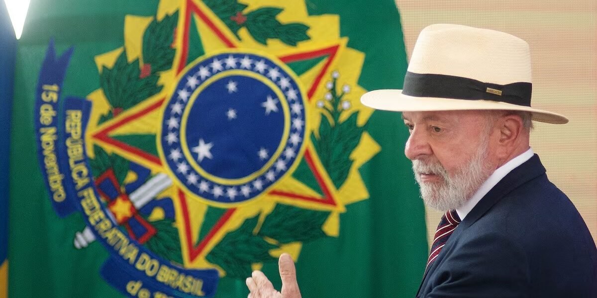 Luiz Inácio Lula da Silva, con sombrero de paja y traje oscuro, gesticula frente a una bandera con el escudo de armas de Brasil