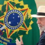 Luiz Inácio Lula da Silva, con sombrero de paja y traje oscuro, gesticula frente a una bandera con el escudo de armas de Brasil
