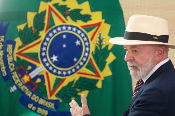 Luiz Inácio Lula da Silva, con sombrero de paja y traje oscuro, gesticula frente a una bandera con el escudo de armas de Brasil