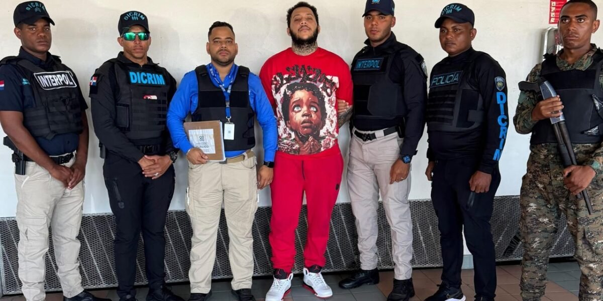 Jhovanny de Jesús Metz Cruz, de camiseta y pantalón rojos, custodiado por agentes de Interpol, la DICRIM, un representante del Ministerio Público y un militar