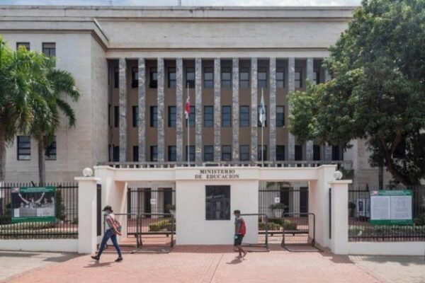 Fachada de la sede del Ministerio de Educación, con columnas, banderas, palmeras y la entrada con el letrero del ministerio