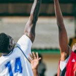 Dos jugadores de baloncesto saltan con los brazos extendidos para disputar el balón