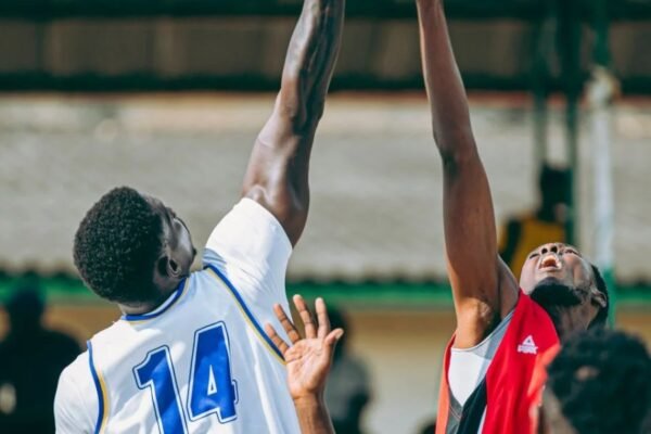 Dos jugadores de baloncesto saltan con los brazos extendidos para disputar el balón